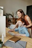 woman looking over should of boy sitting at computer smiling